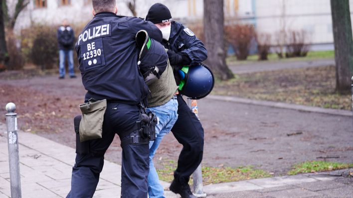 Ein Demonstrant wird von Polizisten neben der Karl-Marx-Allee festgesetzt. (Quelle: dpa/Annette Riedl)