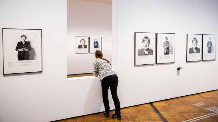 Eine Person lehnt bei einem Presserundgang durch die Ausstellung «Angela Merkel Porträts 1991 – 2021» der Fotografin Herlinde Koelbl im Deutschen Historischen Museum an einer Wandöffnung. (Quelle: dpa/C. Soeder)