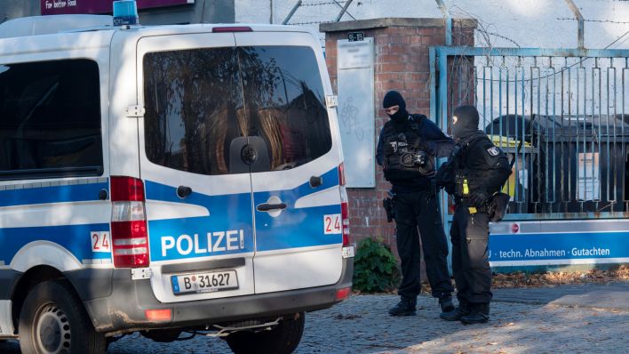 Polizeibeamte stehen an der Zufahrt zu einem Gewerbegebiet in Weißensee. Seit dem frühen Morgen gehen Polizeibeamte gegen die Hells Angels in Berlin und Brandenburg vor. Bei der Razzia sind mehrere hundert Beamte im Einsatz. Nach Behördenangabe geht es um Ermittlungen wegen Drogenhandels und Waffenhandels. (Quelle: dpa/Paul Zinken)