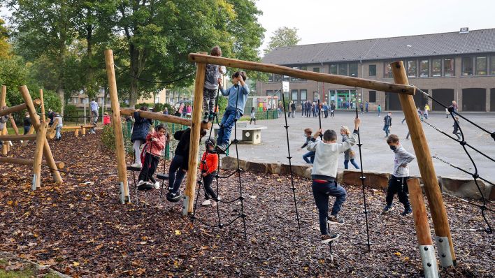 Symbolbild: Kinder spielen am Klettergeruest auf Schulhof-Bereich einer Grundschule. (Quelle: dpa/R. Oberhäuser)