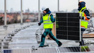 Symbolbild: Arbeiter montieren Solarmodule einer neuen Photovoltaik-Anlage auf dem Dach des Olympiastadions. (Quelle: dpa/M. Hanschke)