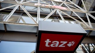 Archivbild: Das Logo der Tageszeitung "taz" ist am Eingang des Redaktionsgebäudes in Berlin-Mitte zu sehen. (Quelle: dpa/S. Braun)
