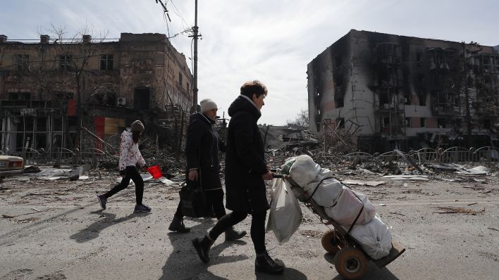 Bewohner gehen am 10. April 2022 in der Nähe von beschädigten Gebäuden in Mariupol. Quelle: (dpa/Victor/XinHua)