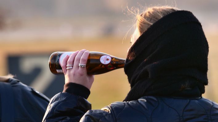 Symbolbild: Eine junge Frau trinkt am 19.03.2022 auf dem Tempelhofer Feld, im Licht der Abendsonne, Bier im Gehen aus der Flasche. (Quelle: dpa/Wolfram Steinberg)