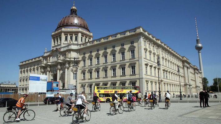 Fahrradtouristen besichtigen auf ihrer Tour durch die Mitte der Hauptstadt, bei Temperaturen um 25 Grad Celsius, das Humboldt-Forum, das nei Berliner Stadtschloss. (Quelle: dpa/Wolfgang Kumm)