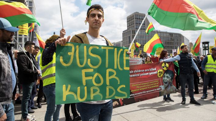 "Justice for Kurds" (Gerechtigkeit für die Kurden) steht auf einem Plakat, das ein Mann während einer Demonstration in Berlin-Mitte hält (Quelle: Presscov/Zuma Press Wire/Michael Kuenne)