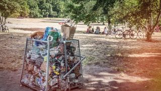 Überfüllte Mülleimer; Menschen, die auf der abgewetzten Wiese sitzen: die Hasenheide in Berlin-Neukölln (Quelle: Picture Alliance/Global Travel Images)
