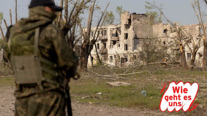 Symbolbild: Ein Soldat in der Ukraine befindet sich für zertrümmerten Häusern in der Region Lugansk. (Quelle: dpa/TASS)