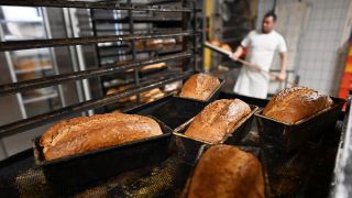 Symbolbild: Bäcker holt Brote aus dem Ofen. (Quelle: dpa/dpa-Zentralbild | Martin Schutt)