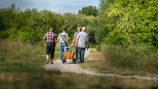 Vier Männer gehen am Vatertag mit einem Bollerwagen, auf dem zwei Kisten Bier stehen. (Quelle: dpa/Guido Kirchner)