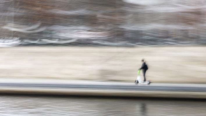 Eine Person auf einem E-Scooter, aufgenommen mit langer Belichtungszeit. (Quelle: dpa/Florian Gaertner)