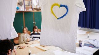 Ein T-Shirt mit einem Herz, umrahmt von den ukrainischen Farben hängt im Klassenraum einer Willkommensklasse am Willy-Graf-Gymnasium in Berlin-Lichterfelde. (Quelle: dpa/Annette Riedl)
