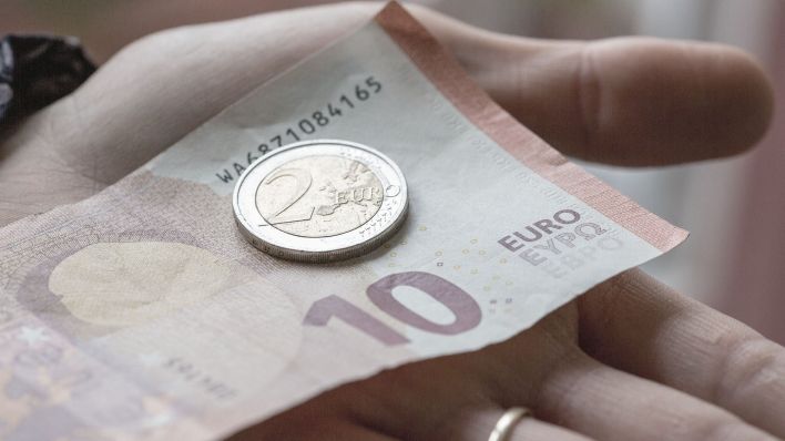 Symbolbild: Eine Person hält 12 Euro in der Hand. (Quelle: dpa/F. Juarez)