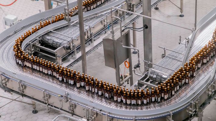 Symbolbild: Flaschen werden auf einem Fließband in einer Brauerei abgefüllt. (Quelle: imago images/V. Isore)