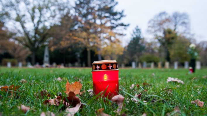 Symbolbild: Eine Kerze steht an einer Grabstätte für anonyme Urnengräber auf einem Friedhof. (Quelle: dpa/H. Dittrich)