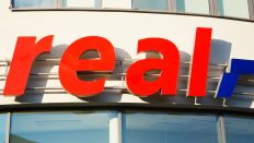 Schriftzug und Logo von real an der Fassade einer Filiale der Lebensmittelkette real. (Quelle: Wolfram Steinbach/dpa)