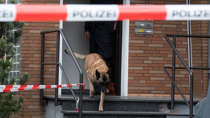 Symbolbild: Ein Drogenspürhund kommt aus dem Eingang zu einem Tatort. (Quelle: dpa/B. Thissen)