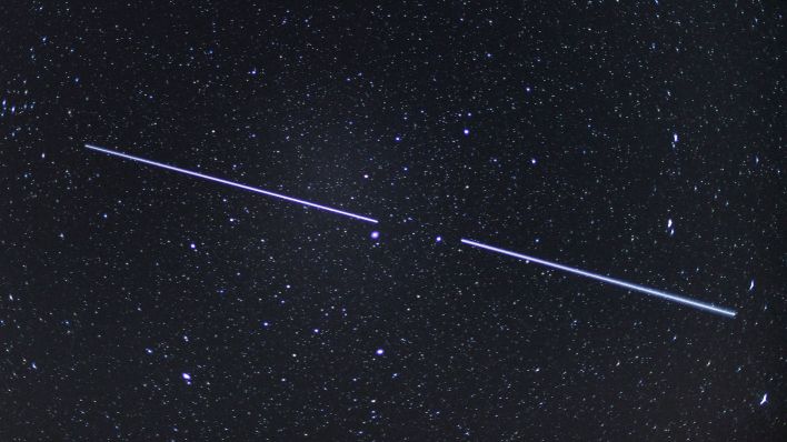 Zwei «Starlink»-Satelliten sind als Lichtstreifen am Nachthimmel zu sehen (Bild: dpa/Patrick Pleul)