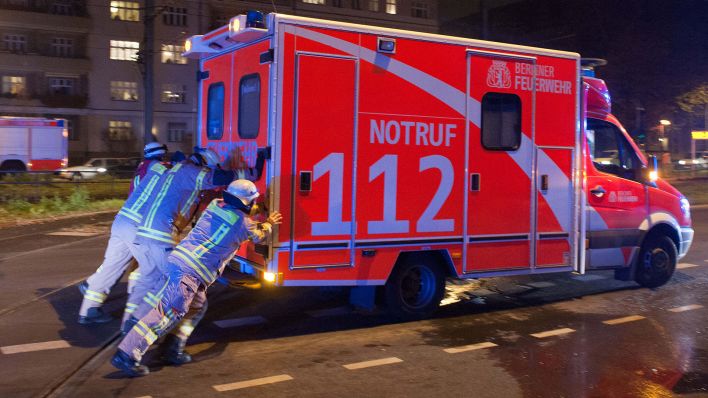 Symbolbild: Feuerwehrmänner schieben in Berlin einen verunglückten Rettungswagen vom Unfallort. (Quelle: dpa/M. Gambarini)
