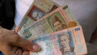 Eine Frau hält mehrere Geldscheine der Ukrainischen Währung Hrywnja (Bild: imago images/Sergienko)