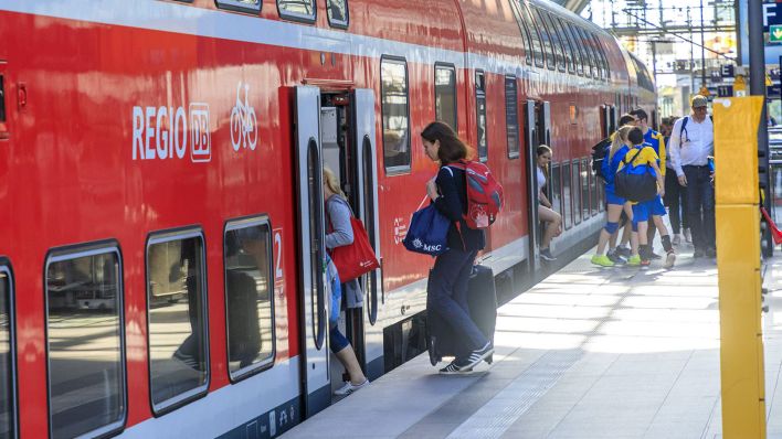 Menschen steigen in einen Zug der DB Regio am Berliner Hauptbahnhof ein (Bild: imago images/Rainer Weisflog)