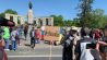 Am Sowjetischen Ehrenmal Tiergarten hält zum Jahrestag des Kriegsendes des zweiten Weltkriegs am 08. Mai 2022 ein Demonstrant ein Schild mit der Aufschrift "Verhandeln" mit aufgezeichneter russischer und ukrainischer Fahne. (Quelle: rbb)