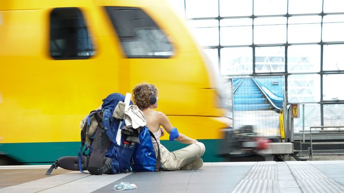 Eine Reisende sitzt am Hauptbahnhof am Bahnsteig und wartet auf ihren Zug. (Quelle: dpa/Joerg Carstensen)