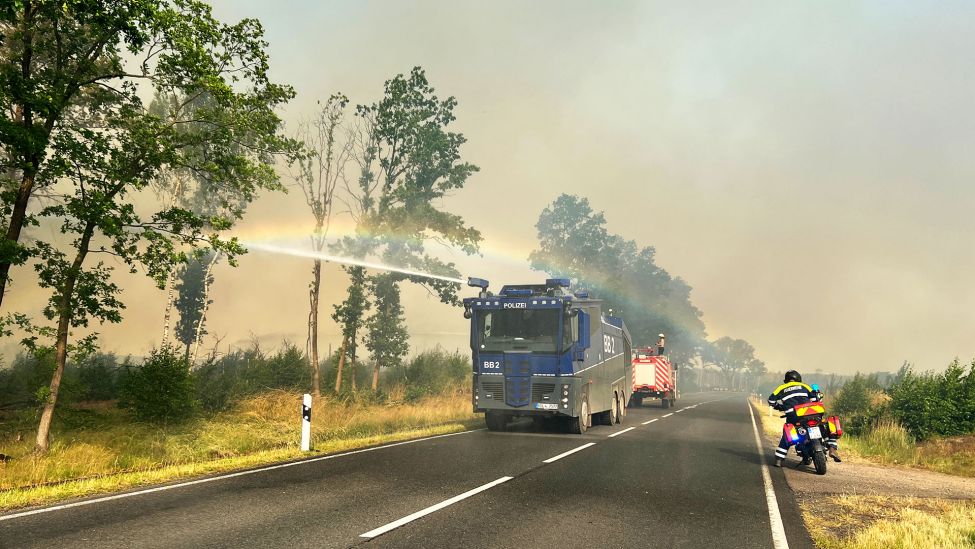 Ein Wasserwerfer der Polizei ist in einem Waldstück bei einem Waldbrand im Einsatz. (Quelle: dpa/T.Schulz)