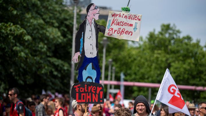 Ein Teilnehmer der Demonstration der Gewerkschaft Erziehung und Wissenschaft (GEW) trägt am 29.06.2022 ein Plakat mit der Aufschrift "verbindliche Klassengrößen - Fairer Lohn". (Quelle: dpa/Christophe Gateau)