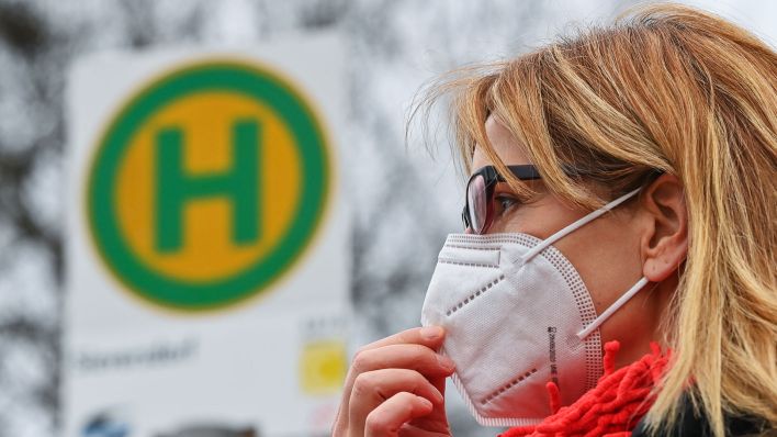 Eine Frau trägt eine FFP2 Schutzmaske an einer Bushaltestelle. (Quelle:dpa/P.Pleul)
