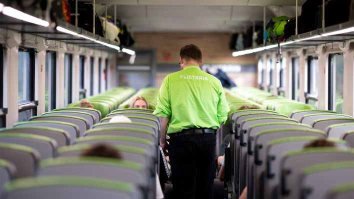 Ein Zugbegleiter geht während einer Fahrtdurch einen Flixtrain und kontrolliert die Fahrscheine (Bild: dpa/Daniel Reinhardt)