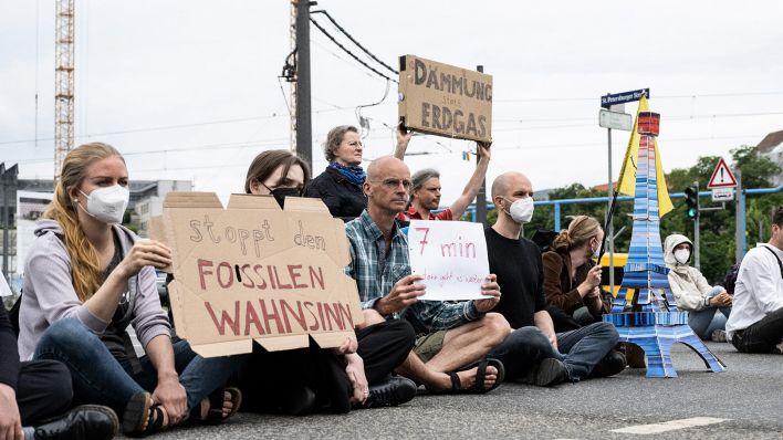 Umweltaktivisten der Gruppe «Letzte Generation» sitzen während einer Demonstration auf der Fahrbahn an einer Ampelkreuzung (Bild: dpa/Sebastian Kahnert)