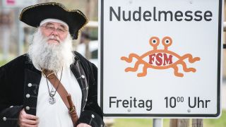 Rüdiger Weida von der «Kirche der fliegenden Spaghettimonster» steht neben seinem Schild "Nudelmesse" in Templin (Bild: dpa/Patrick Pleul)
