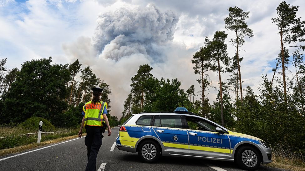 Ein Polizei Auto sperrt die Straße in einem Waldbrandgebiet in der Gohrischheide ab (Bild: dpa/Robert Michael)