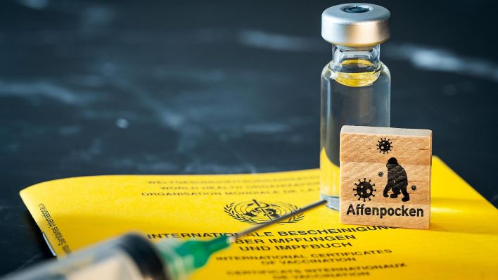 Symbolbild: Impfpass der WHO - Weltgesundheitsorganisation, eine Spritze und einem Holzwürfel mit Aufschrift: Affenpocken. (Quelle: dpa/M. Bihlmayer)