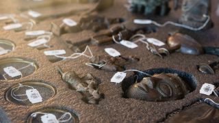Archivbild: Benin-Bronzen mit ihren Inventarschildern liegen in einem Depotkasten im Museum. (Quelle: dpa/M. Becker)