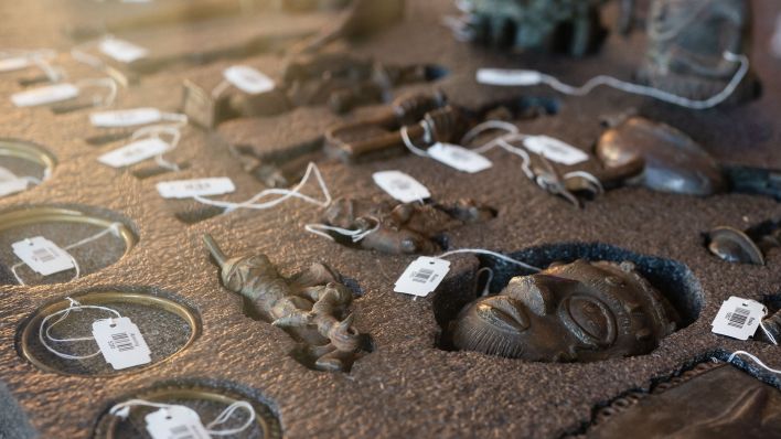 Archivbild: Benin-Bronzen mit ihren Inventarschildern liegen in einem Depotkasten im Museum. (Quelle: dpa/M. Becker)