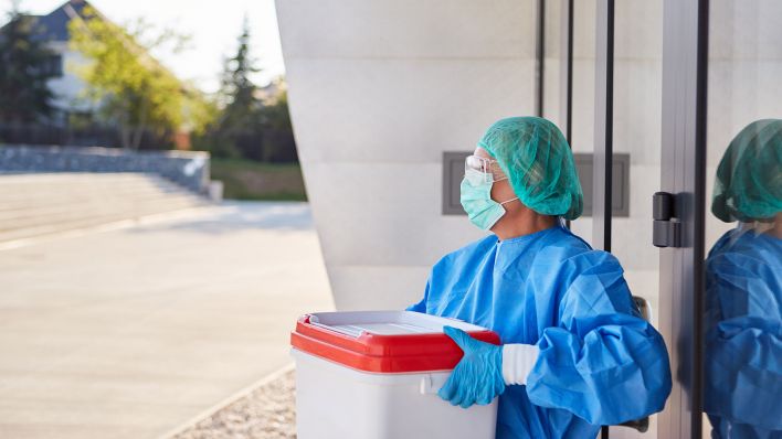 Arzt oder Chirurg mit Organtransport nach Organspende für Operation vor Klinik Eingang in Schutzkleidung (Quelle: dpa/Robert Kneschke)