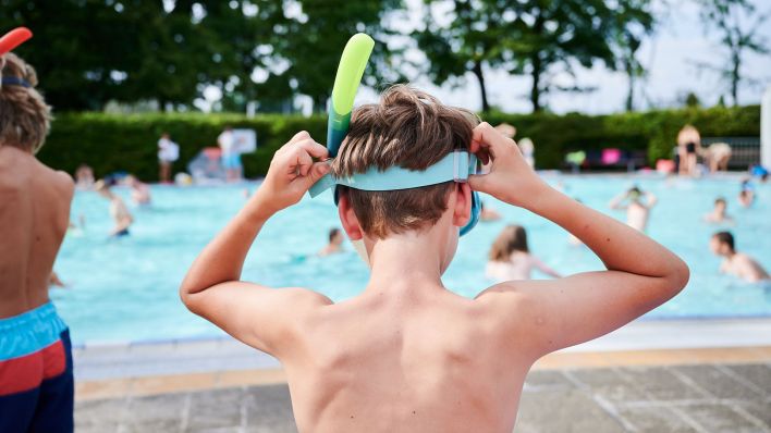Ein Kind setzt sich seine Taucherbrille im Sommerbad Olympiastadion auf. (Quelle: dpa/Annette Riedl)