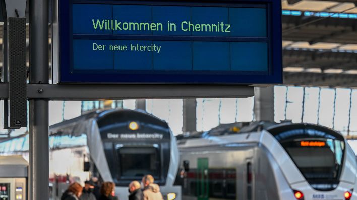 "Willkommen in Chemnitz" steht auf einer Anzeigetafel im Hauptbahnhof in Chemnitz vor einem Intercity (l) der Deutschen Bahn (DB). (Quelle: dpa/Hendrik Schmidt)
