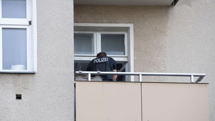 Symbolbild: Ein Polizist steht auf einem Balkon eines Wohnhauses. (Quelle: dpa/Paul Zinken)