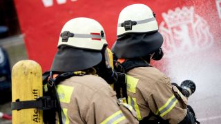 Archiv: Feuerwehrmaenner im Schutzanzug loeschen einen kontrollierten Brand bei einer Vorfuehrung der Berliner Feuerwehr in einem nachgestelltes Wohnzimmer. (Foto: Zacharie Scheurer/ dpa Themendienst)