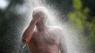 Ein Mann steht an einem Badesee unter einer Dusche. (Foto: Thomas Warnack/dpa)