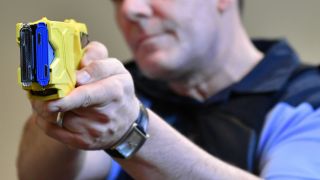 Ein Polizeibeamter zeigt die Handhabung einer Elektroimpulswaffe (Taser) (Quelle: dpa/Paul Zinken)