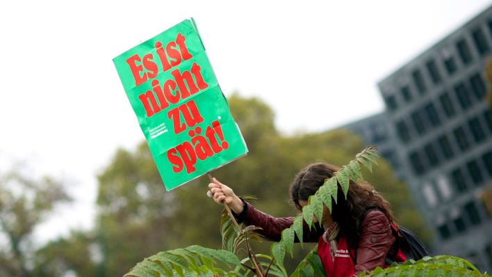 Eine Person hält ein Plakat zum Volksentscheid "Berlin 2030 Klimaneutral" in der Hand