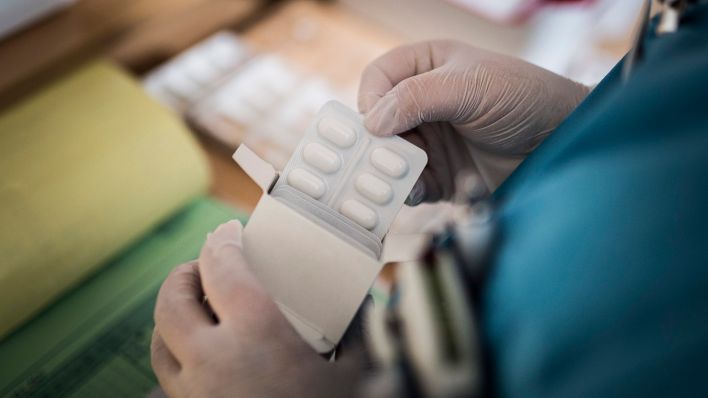 Eine Pflegekraft entnimmt Medikamente aus einer Schachtel (Quelle: dpa/Florian Gaertner)