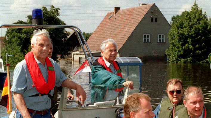 In einem Polizeiboot fährt der Ministerpräsident von Brandenburg, Manfred Stolpe (Mitte, stehend), am30.07.97 durch die vom Oder-Hochwasser überflutete Ernst-Thälmann-Siedlung südlich von Frankfurt (Oder). (Quelle: dpa/Carsten Rehder)