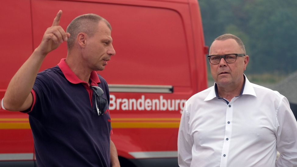 Michael Stübgen (CDU, r) Innenminister des Landes Brandenburg, spricht am 26.07.2022 mit Ronny Neupert von der Freiwilligen Feuerwehr. (Quelle: dpa/Sebastian Willnow)