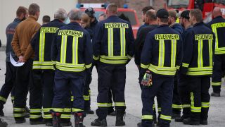 Feuerwehrleute nehmen am 26.07.2022 an einer Einsatzbesprechung am Flughafen Lönnewitz-Falkenberg teil. (Quelle: dpa/Jan Woitas)