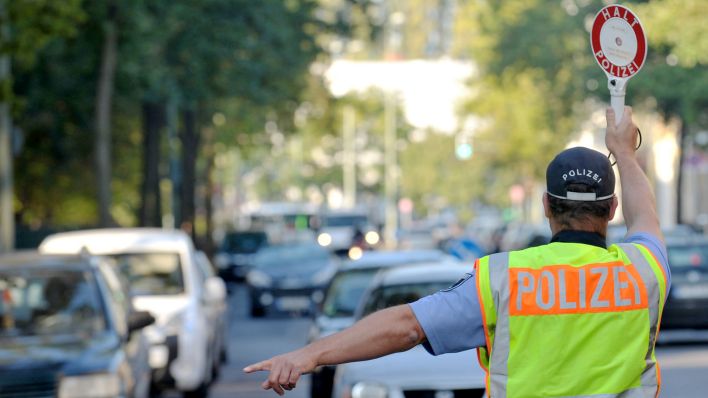 Symbolbild: Ein Polizist steht am 18.09.2014 in Berlin und winkt ein Fahrzeug mit einer Kelle zu einer Kontrollstelle. (Quelle: dpa/Paul Zinken)